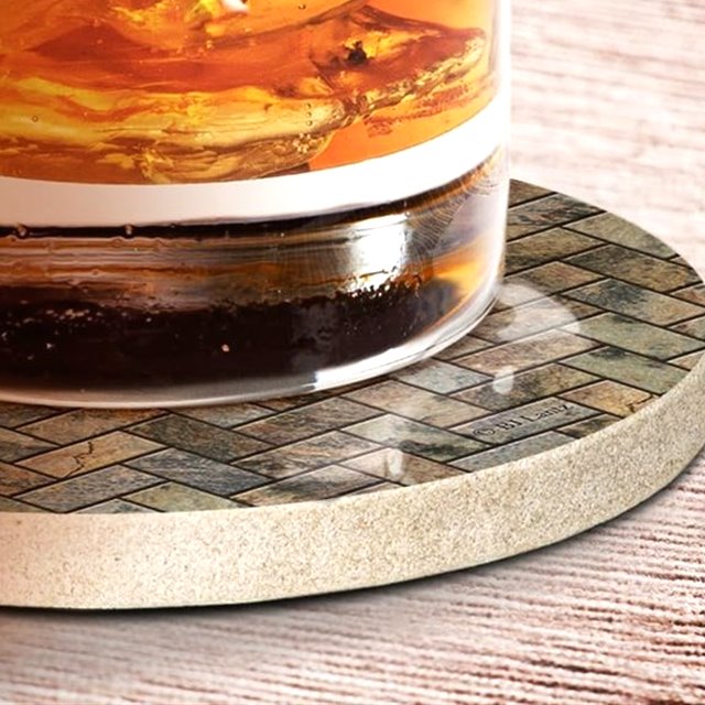 A cold glass sitting on a herringbone printed coaster, condensation collecting at the base