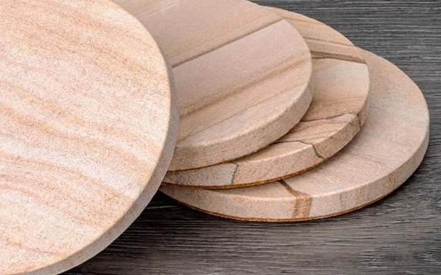 Stack of natural sandstone coasters showing the banded stone edge
